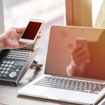 1-voip voip services residential plans hand holding smartphone laptop and voip phone on the desk